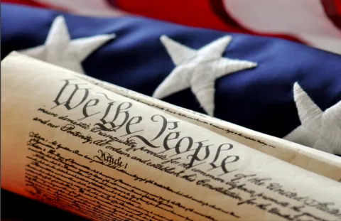 Preamble of the Constitution with U. S. flag behind. 